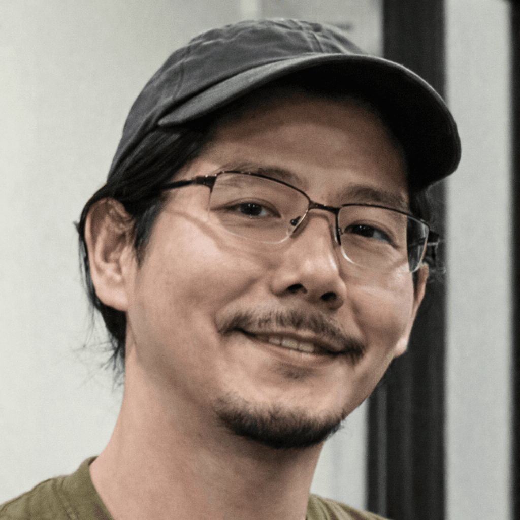 Smiling man with glasses, a mustache, and a goatee wearing a dark baseball cap.