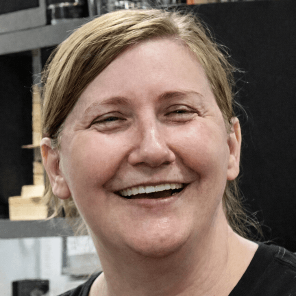Close-up portrait of a woman with blonde hair smiling broadly and showing her teeth.